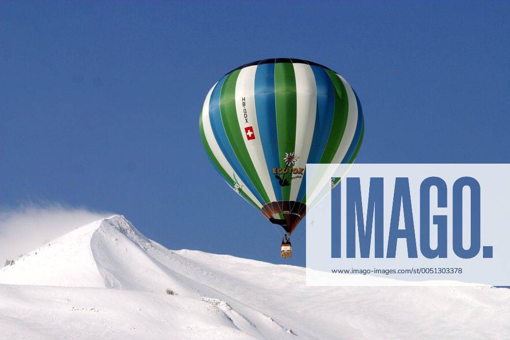 Gestreifter Heißluftballon über schneebedeckten Bergen anlässlich der