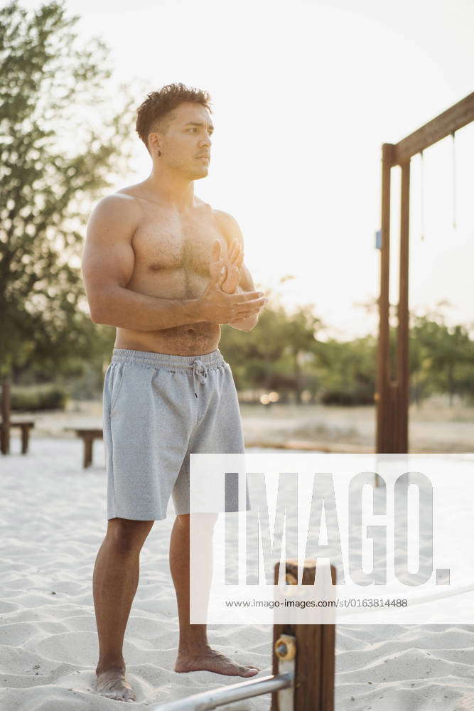 Muscular Hispanic Ethnic Male Athlete With Naked Torso Rubbing Sand On