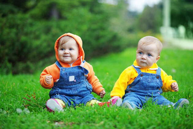 Cute Twins Babies Sitting On Fresh Green Grass In Park Model Released