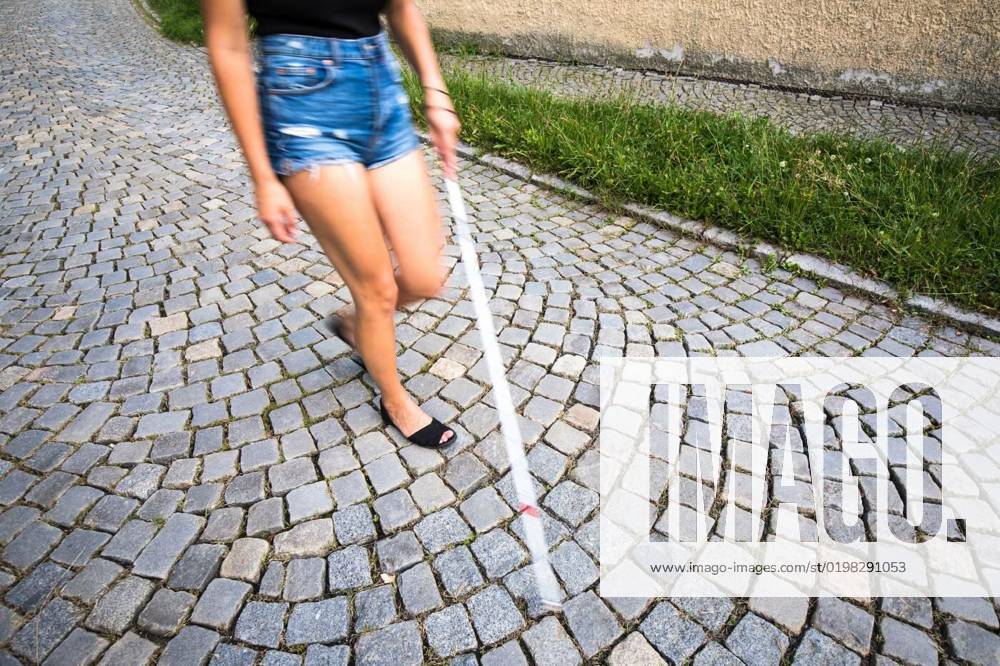 Blind Woman Walking On City Streets Using Her White Cane To Navigate