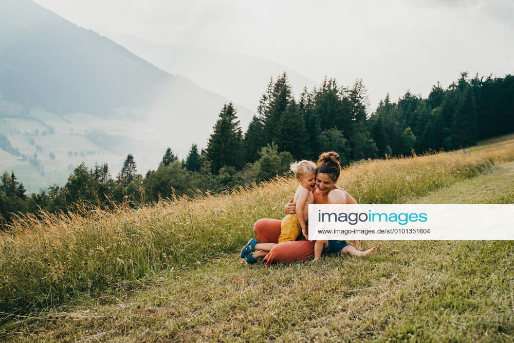 IMAGO Creative, Jahreszeit Sommer, Sommerferien Mom and kids hugging in the mountains sitting on ground Maria Alm, Salzburg, Austria CR_TANI200518-373645-01,model released, Symbolfoto