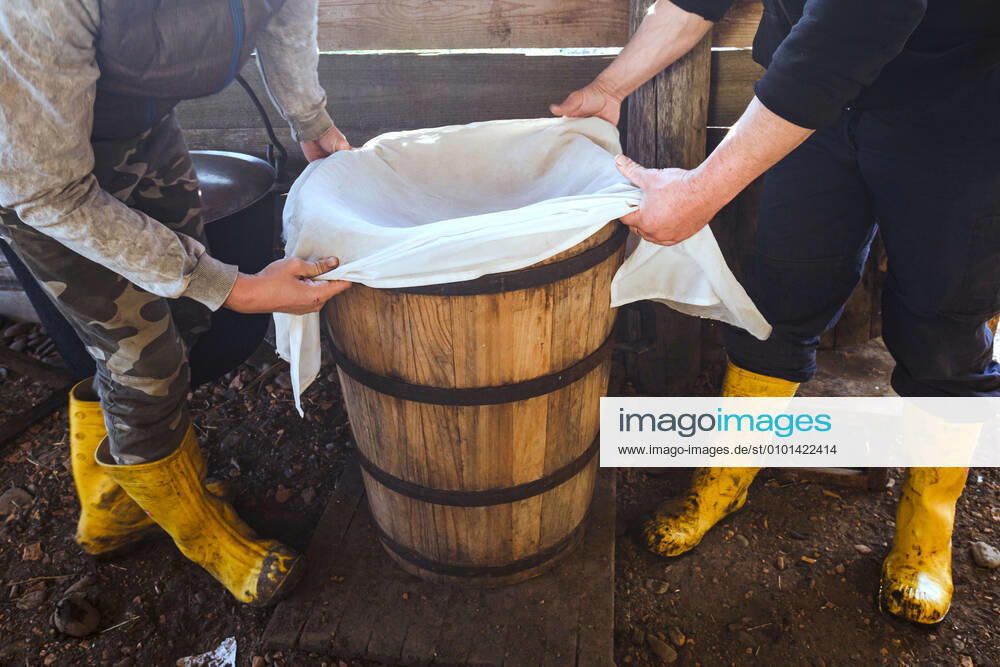 ZAKARPATIA REGION, UKRAINE - Men hold a gauze cloth over the barrel, Khust district, Zakarpattia Region, western Ukraine. Cheese making by shepherds of Zakarpattia Region