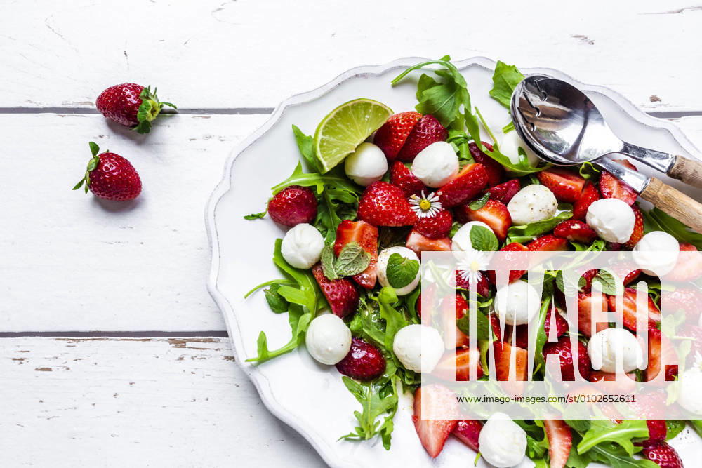 Plate of vegetarian summer salad with lime, arugula, strawberries, mozzarella, mint and daisies SARF04600