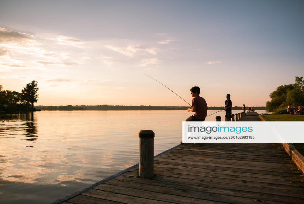 IMAGO Creative, Jahreszeit Sommer, Sommerferien Boys fishing on the dock of a lake at sunset in Ontario, Canada. Kingston, ON, Canada CR_DOHO200803D-455967-01 ,model released, Symbolfoto