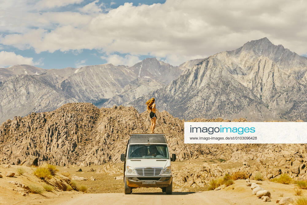 IMAGO Creative: Klimawandel - Nachhaltiges Reisen Young woman on roof of camper van on road in northern California. Lone Pine, CA, United States CR_JUSLKY200806-466838-01 ,model released, Symbolfoto ,property released