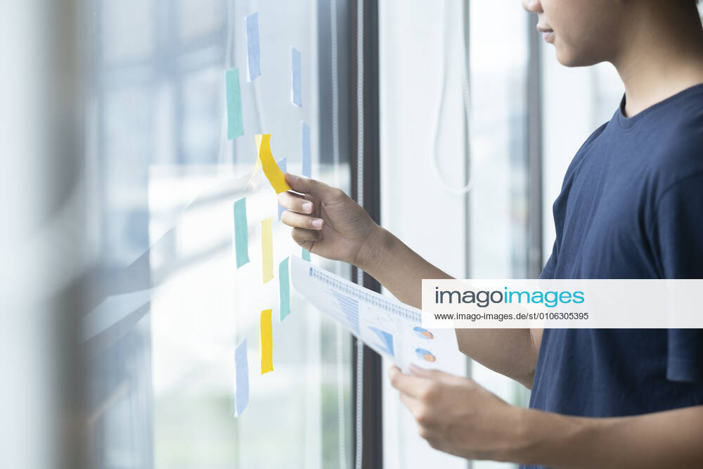 Creative man reading sticky notes on glass wall Chiang Mai, ?.?????????, Thailand CR_SIME201026A-537648-01 ,model released, Symbolfoto
