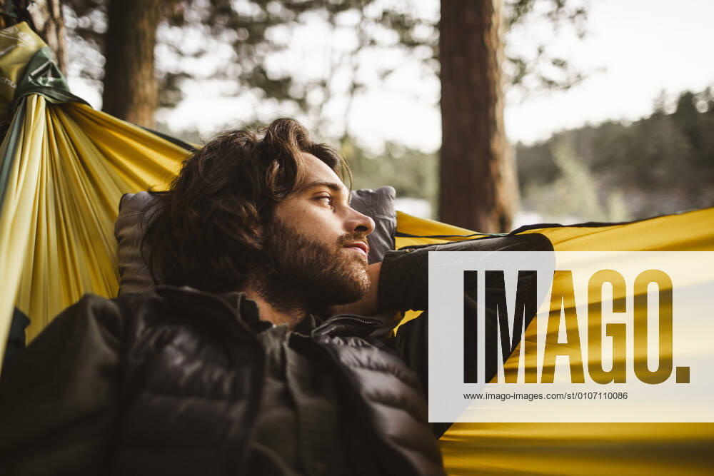 IMAGO Creative: Klimawandel - Nachhaltiges Reisen Contemplating man looking away while lying over hammock in forest, MA82659, Sweden, Stockholm, model released