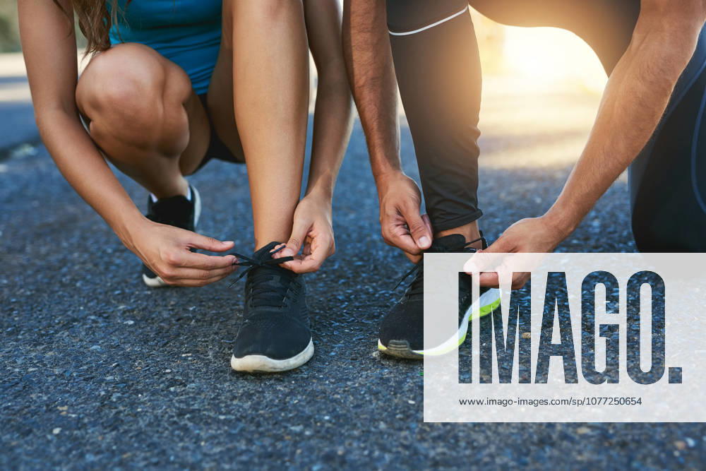 Tie up and hit the road together. a couple tying their shoelaces while out for a run (License=RF) 20262259 ,model released, Symbolfoto