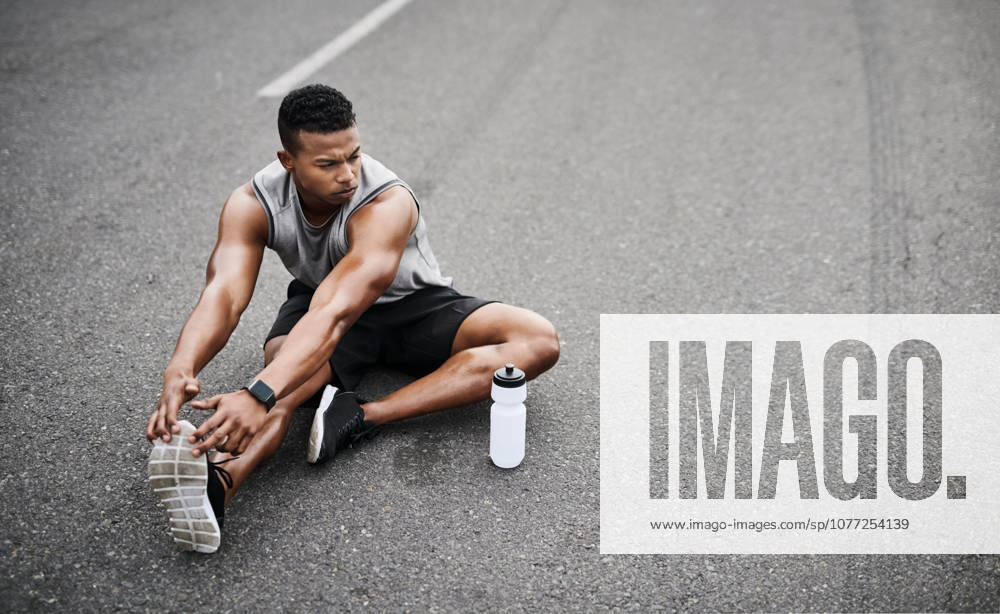 His determination is unfaltering. a sporty young man stretching his legs while exercising outdoors (License=RF) 20287126 ,model released, Symbolfoto