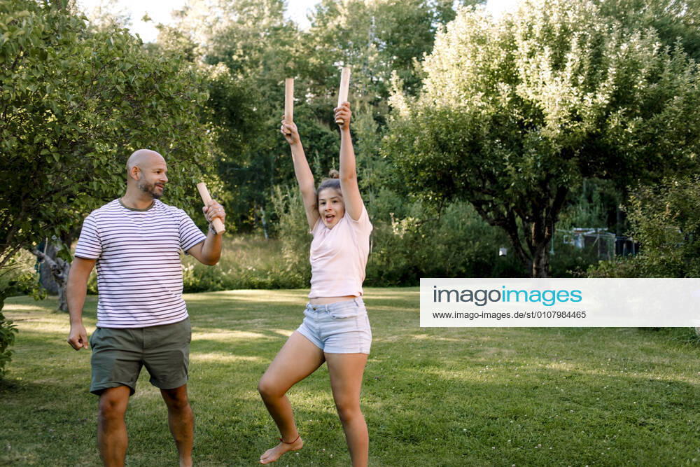 Father looking at daughter with hand raised while playing molkky in yard, MA82696, Sweden, Stockholm Archipelago, model released