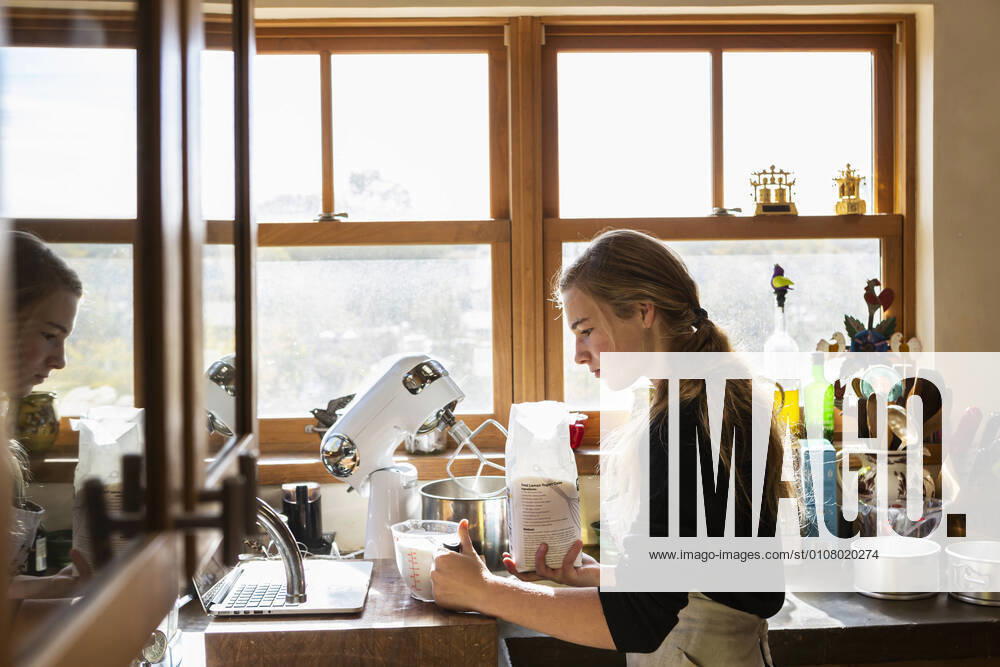 IMAGO Creative: Haushaltsgeräte - Küchenmaschine Teenage girl in a kitchen following a baking recipe on a laptop. Teenage girl in a kitchen following a baking recipe on a laptop. Teenage girl in a kitchen following a baking recipe on a laptop.