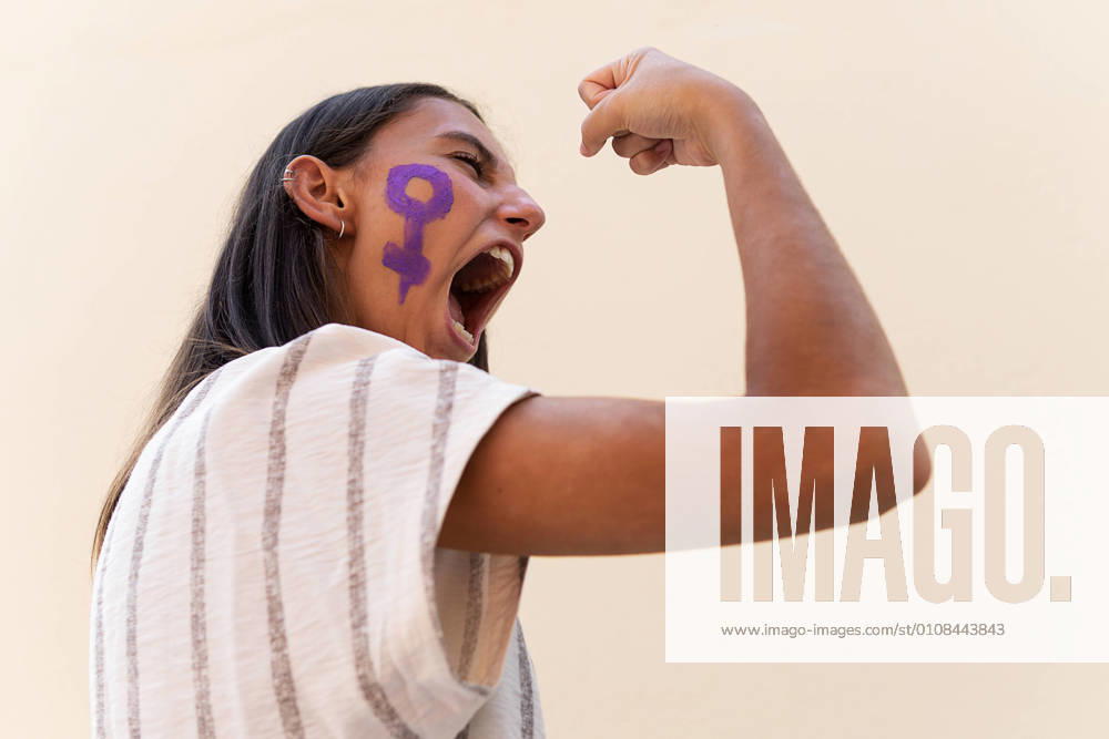IMAGO Creative: Gesellschaft, Integration Side view low angle of determined female with gender symbol on face demonstrating muscles while showing girl power concept