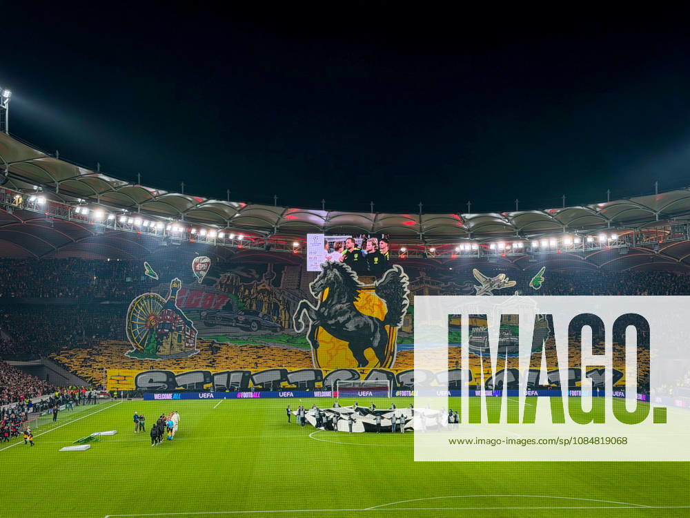 Germany, Soccer, 2026–2027 UEFA Champions League, Matchday 3, VfB Stuttgart vs. Atlético Madrid, October 20, 2026, Stuttgart Arena, interior view; wide shot of the illuminated soccer stadium from behind the goal before kickoff; large fan choreography by VfB supporters in the Cannstatter Kurve; packed stands; spectators; fans; floodlights; stadium roof; playing field; center circle; Champions League anthem, player entrance ceremony, fan section, atmosphere, home game, UEFA, Champions League, advertising, sponsors