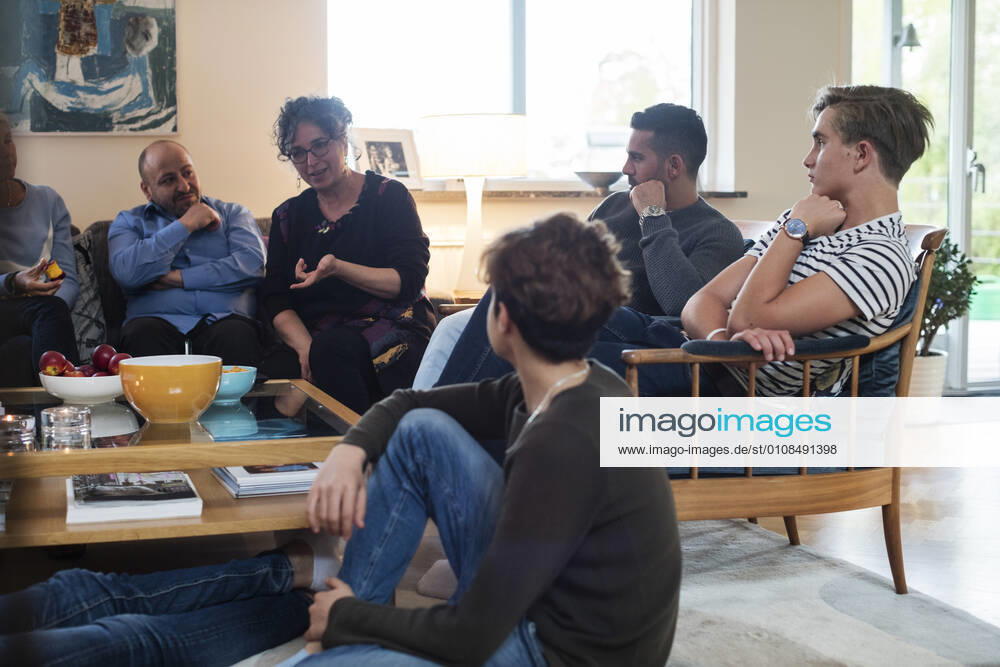 Multi-ethnic friends and family talking while sitting in living room , model released, property released