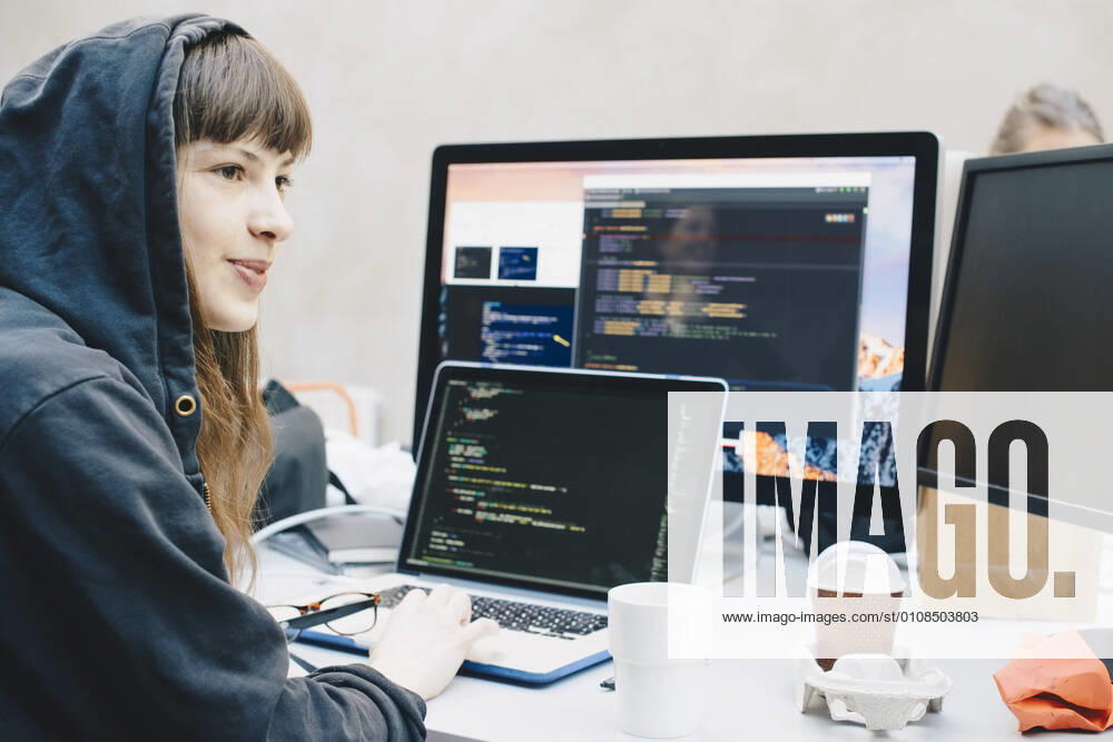 Side view of female computer programmer looking away while using laptop at desk in office , model released, property released