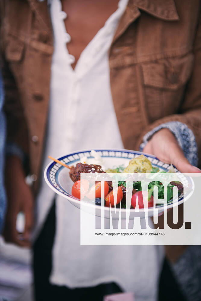 IMAGO Creative: Landleben - Essen Midsection of woman holding meal in plate during social gathering on terrace , model released, property released