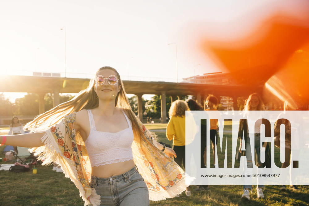 Smiling woman dancing with friends in background at event on sunny day , model released