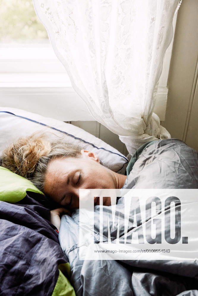 IMAGO Creative, Jahreszeit Sommer, Sommerferien High angle view of mid adult woman sleeping on bed in cottage , model released, property released