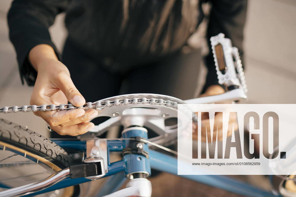 IMAGO Creative: Klimawandel - Nachhaltiges Reisen Midsection of businesswoman repairing bicycle in city , model released
