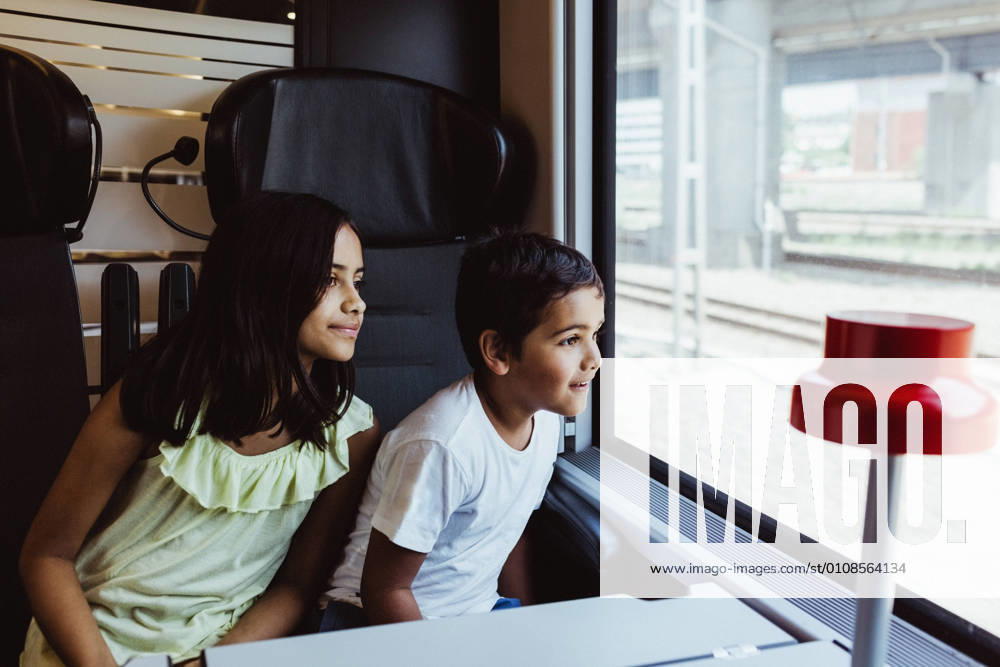 Siblings looking through train window while traveling together , model released, property released