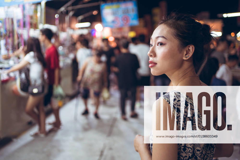 IMAGO Creative, Jahreszeit Sommer, Sommer in der Stadt IMAGO Creative: Ruhe im Chaos Side view of confident ethnic female standing on crowded street in Night Market in Taiwan and looking away