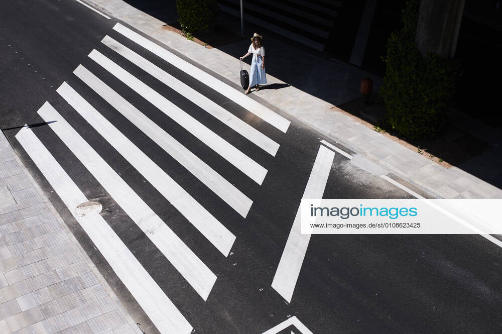 Top view of young woman with baggage crossing a street at the airport model released Symbolfoto IGGF01340