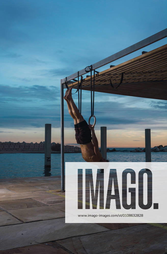 IMAGO Creative, Jahreszeit Sommer, Sommer in der Stadt Athletic man balancing on gymnastic rings, Model released