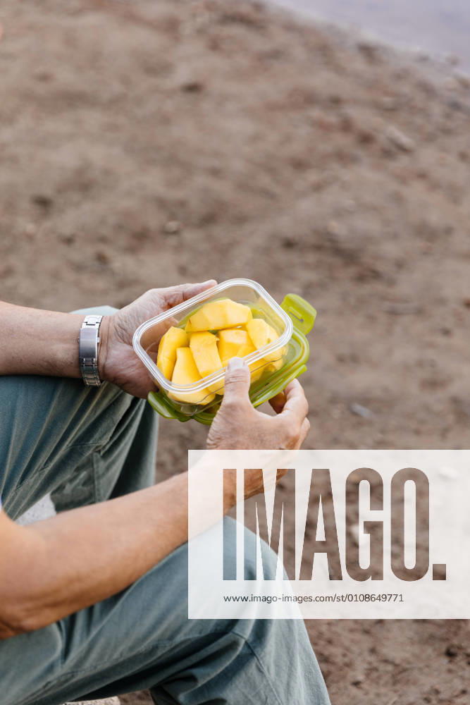 Detail of unrecognizable man eating mango fruit in the forest, Model released