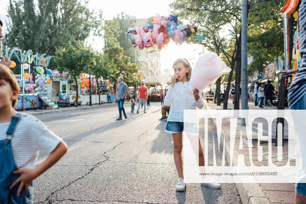 IMAGO Creative, Jahreszeit Sommer, Sommer in der Stadt Cheerful girl eating cotton candy on street, Model released