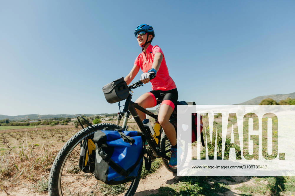 IMAGO Creative: Klimawandel - Nachhaltiges Reisen Lady in sportswear and helmet riding bike on stony path while traveling through forest on sunny day in countryside