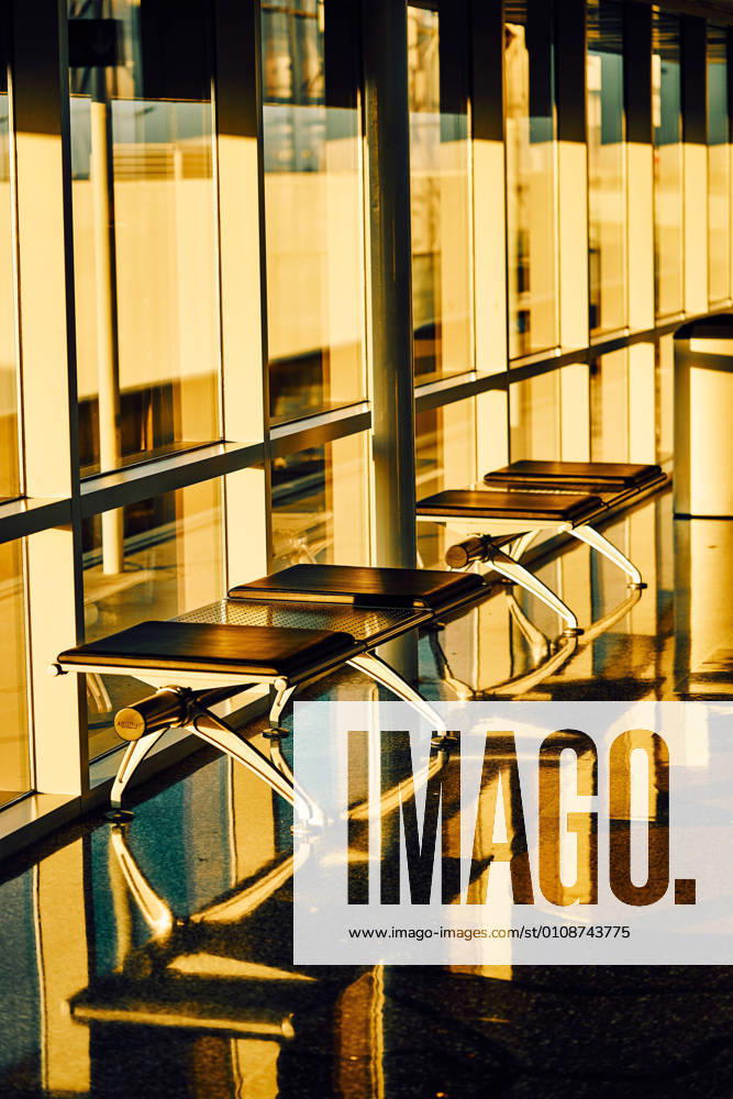 Metal bench with leather black seats along glass wall in sunny hallway of airport in Texas