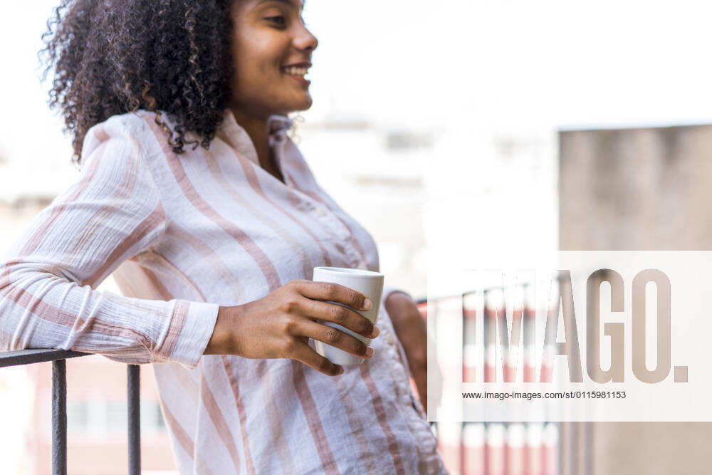 Smiling young female entrepreneur leaning on railing during coffee break at office model released Symbolfoto property released AFVF08426