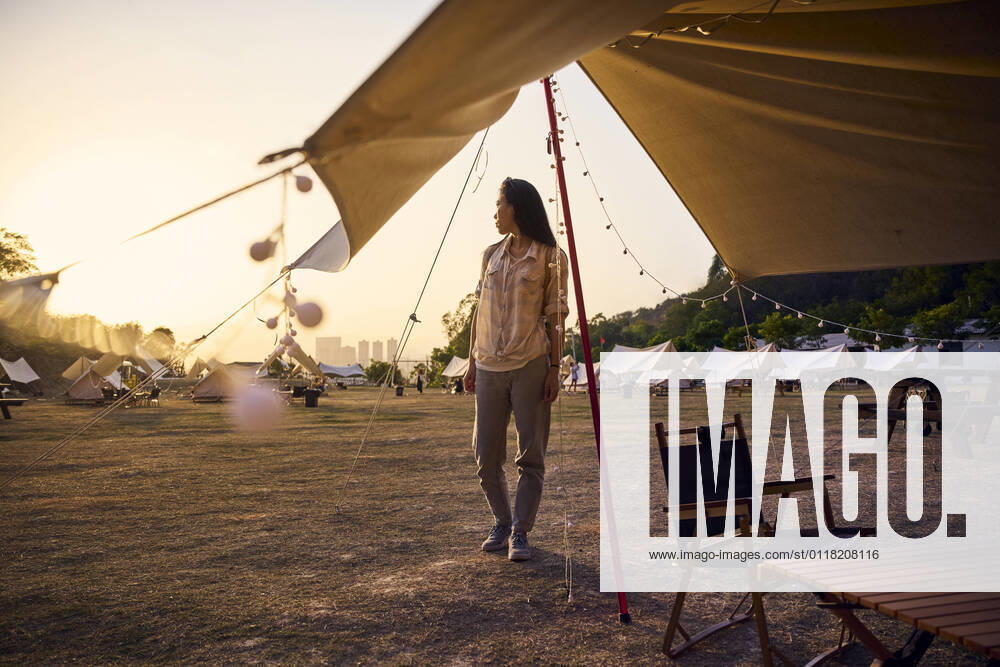 IMAGO Creative: Ende des Sommers Ethnic Asian woman with sunglasses having a relaxing time standing looking away in camping area during sunset time
