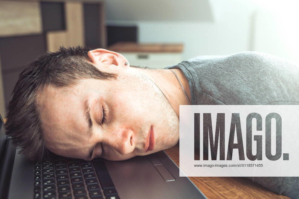 Bavaria, Germany - 18 May 2021: tired man sleeps on his notebook at work in home office - he lies with head on keyboard