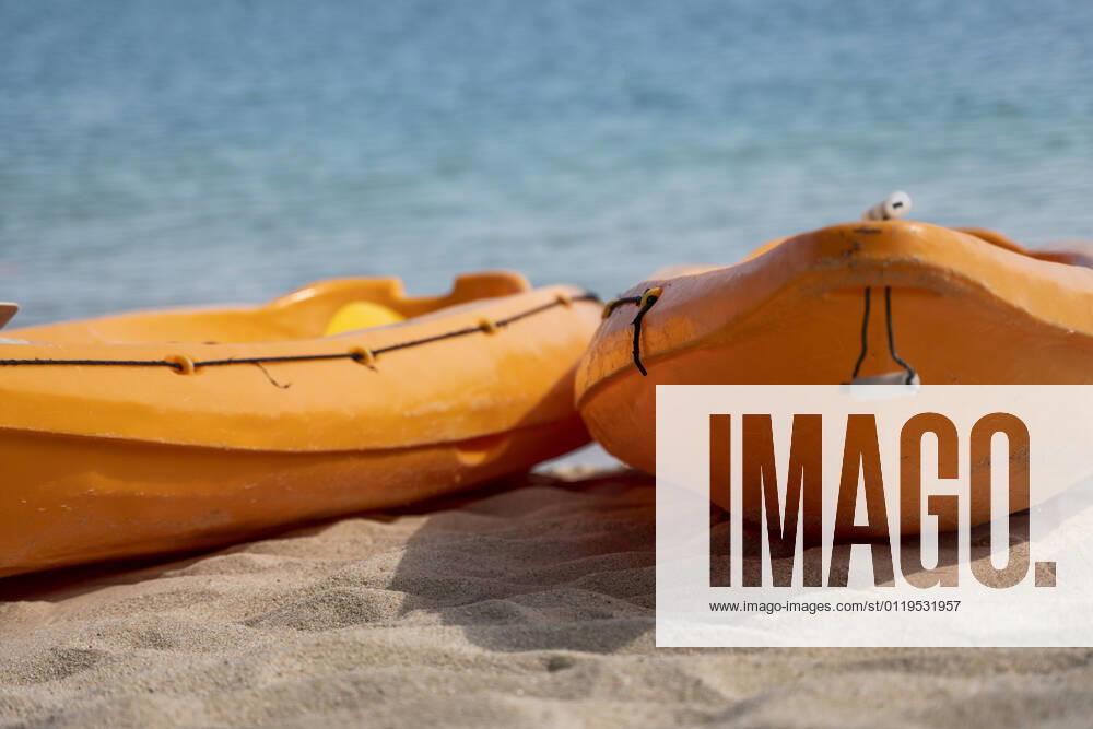 IMAGO Creative: Sommer Sport - Strand Two colorful orange kayaks on a sandy beach ready for paddlers in sunny day. Several orange recreational boats on the sand. Active tourism and water recreation. Two colorful orange kayaks on a sandy beach ready for paddlers in sunny day. Several orange recreational boats on the sand. Active tourism and water recreation
