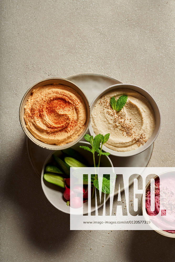 IMAGO Creative, Food, Hummus Top view of bowls with assorted hummus served on table with fresh cucumbers and radish