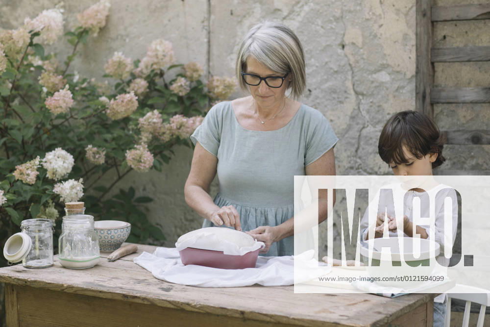 Grandmother preparing bread by grandson playing with dough at back yard model released Symbolfoto property released ALBF01608