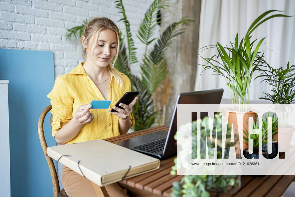 Female professional doing online payment through credit card while sitting at home office model released Symbolfoto property released RCPF01030