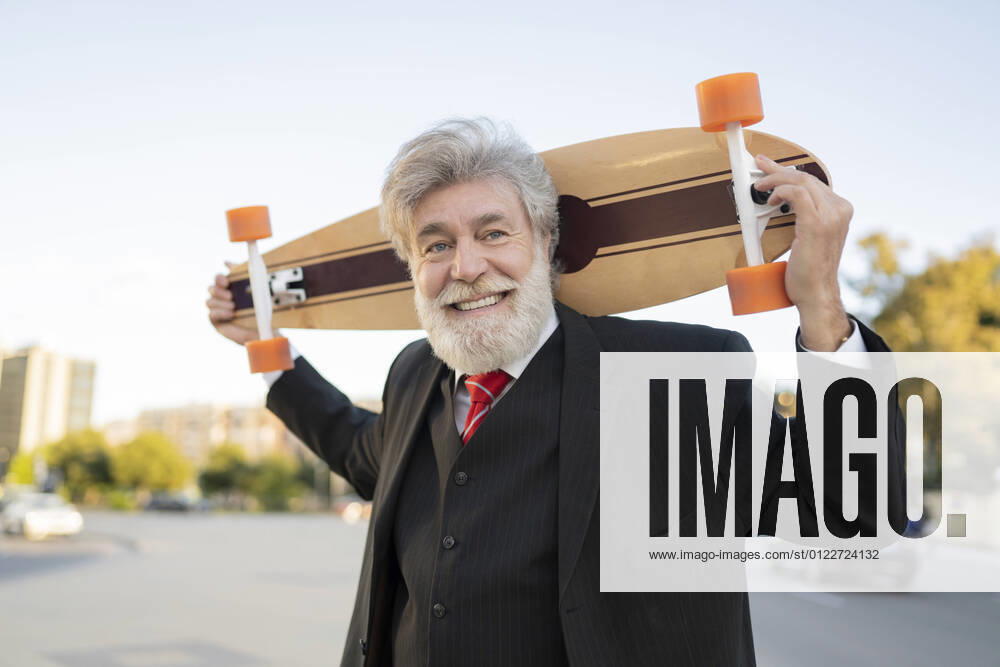 Smiling businessman carrying skateboard in city model released Symbolfoto JCCMF02620