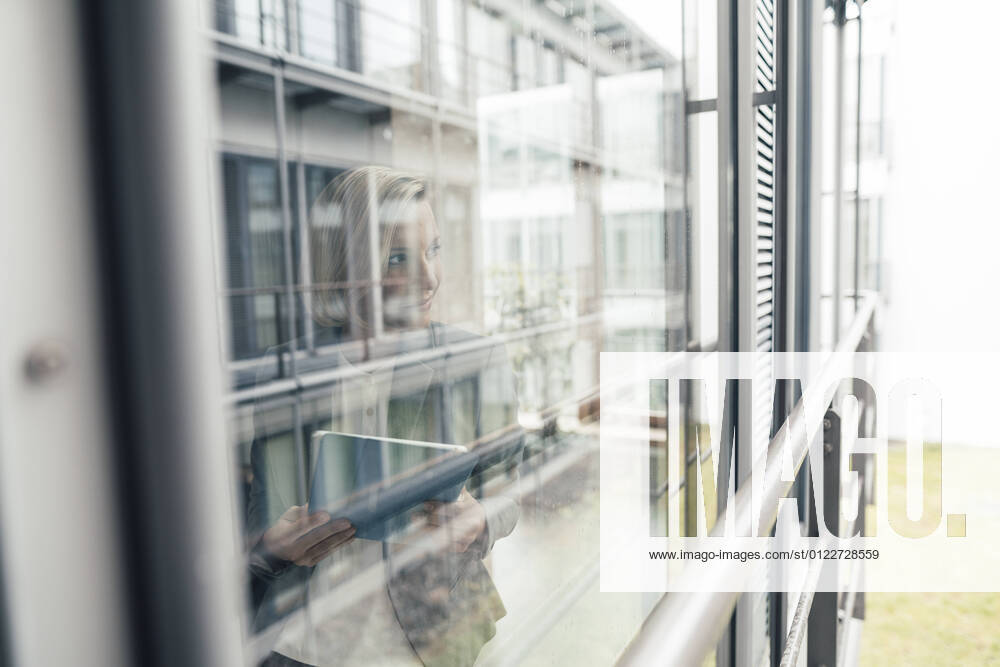 Businesswoman with digital tablet looking through office window model released Symbolfoto property released JOSEF04792