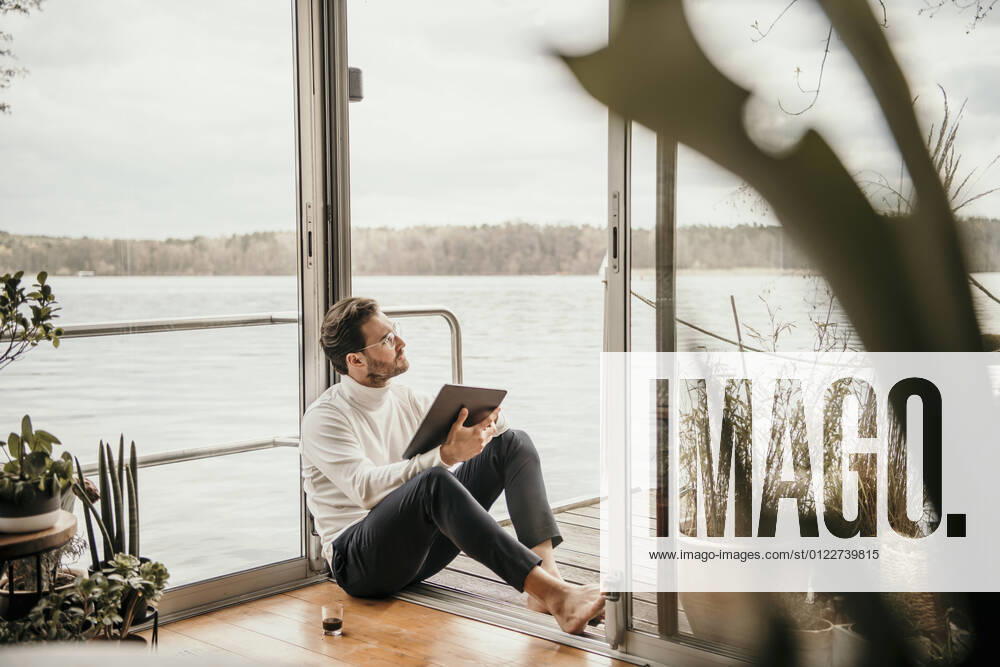 Male professional looking away while sitting with digital tablet on houseboat model released Symbolfoto property released MJRF00508