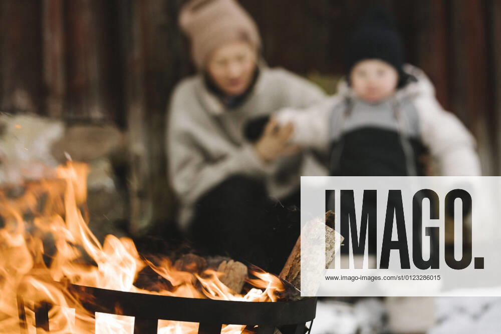 Burning wood in fire pit against woman and daughter during winter Sweden, Vastergotland, model released, property released