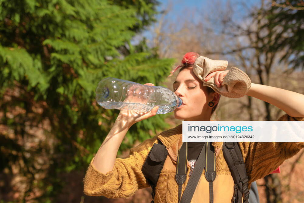 IMAGO Creative, Gesellschaft, Leisure Sickness Thirsty female traveler with backpack enjoying fresh water on sunny day in nature, Model released