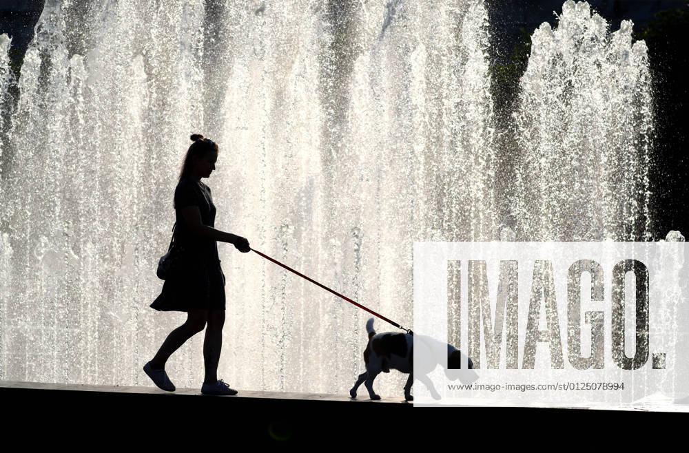 A woman walks a dog past a fountain near Finland railway station. Peter Kovalev TASS TS107D23