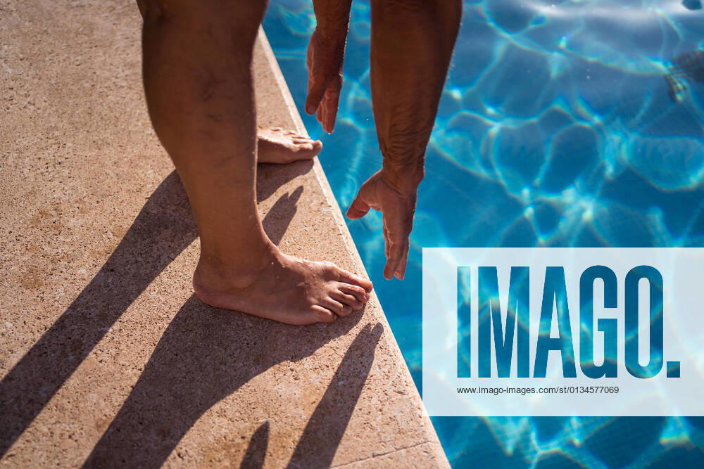 High angle of crop anonymous barefoot person stretching forward while standing on poolside edge near clean water, Model released JuanAlbertoRuiz_FamilyAtPool_148.jpg