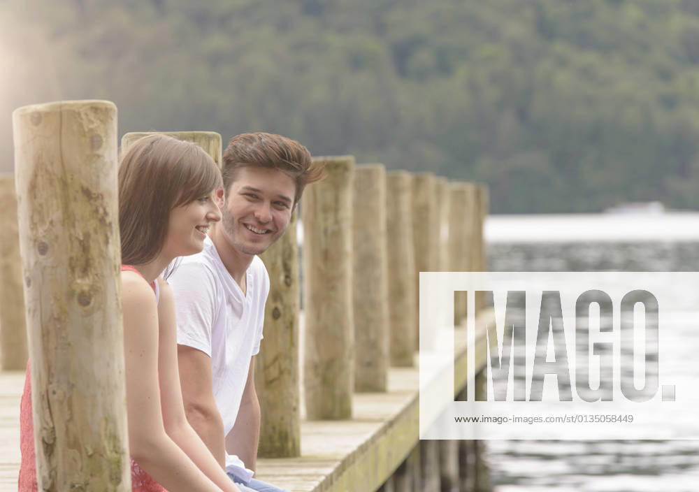 IMAGO Creative, Jahreszeit Sommer, Sommerferien Young couple laughing together on jetty over lake, 06.10.2014,