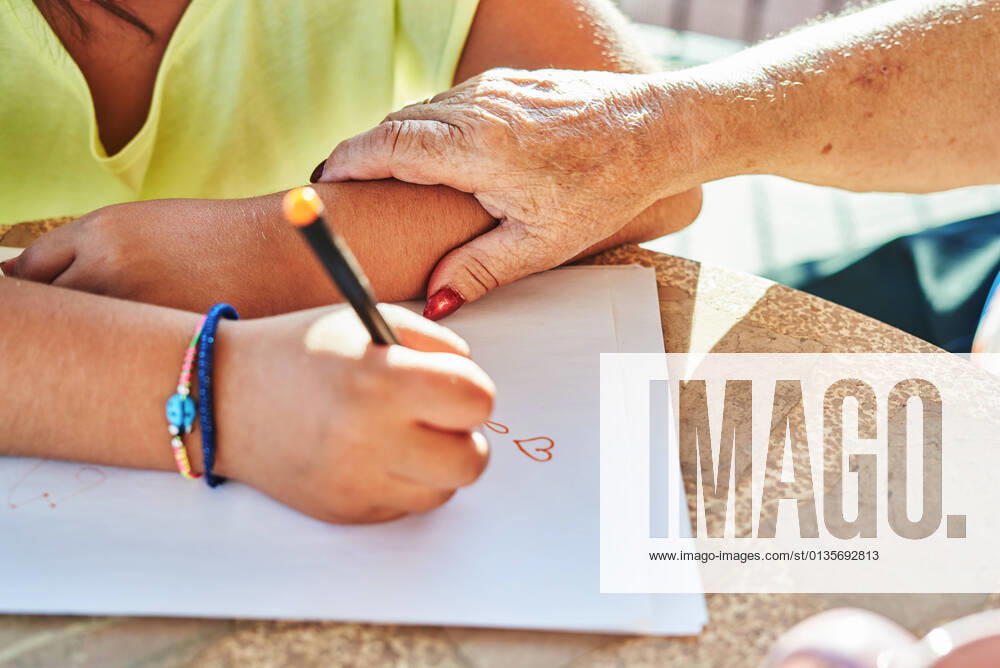 IMAGO Creative: Gesellschaft, Integration From above of crop unrecognizable grandmother touching arm of anonymous granddaughter sitting at table and drawing on paper in sunny day, Model released AdalbertoRodriguez_GrandmotherAndGranddaughter_6.jpg
