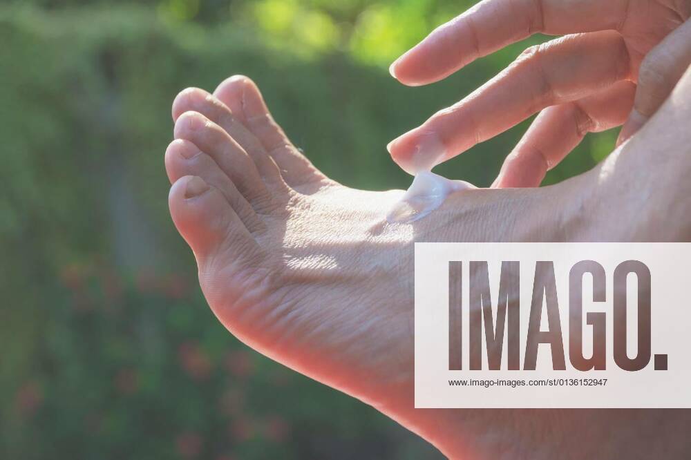 IMAGO Creative, Jahreszeit Sommer, Sonnenschutz hand of woman apply lotion on skin of back foot on nature background., 12.10.2020,