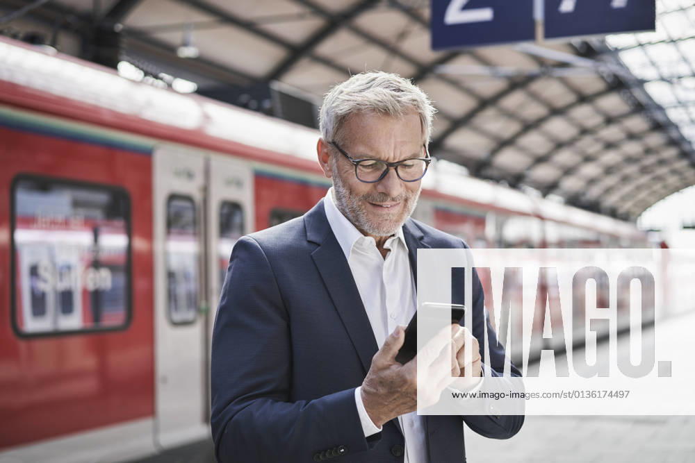 IMAGO Creative: Neue Aussichten Male professional using mobile phone while standing on railroad platform model released Symbolfoto RORF02834