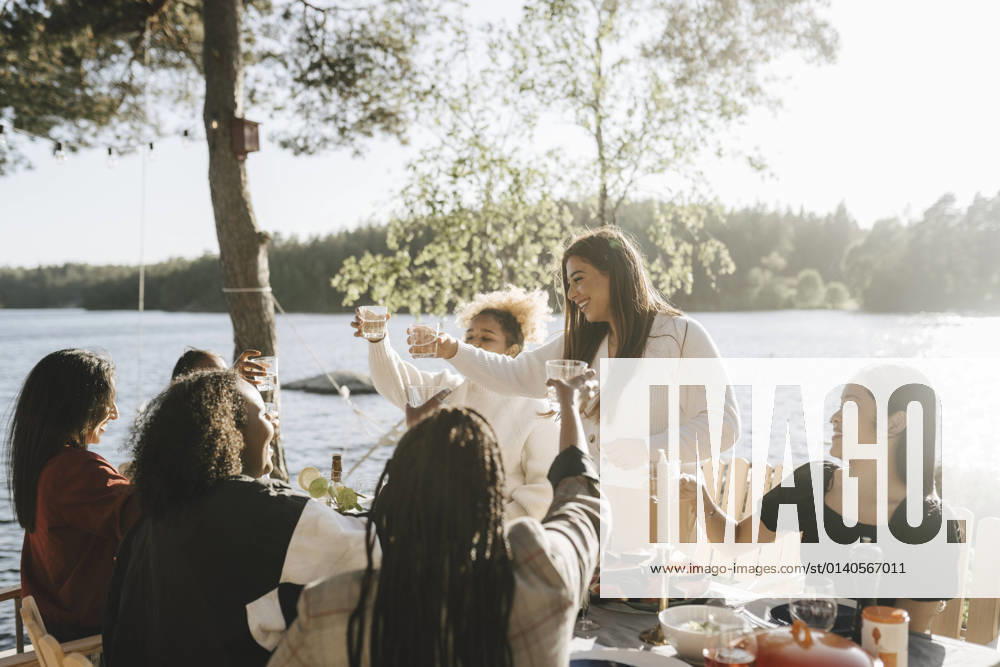 IMAGO Creative, Jahreszeit Sommer, Sommer in der Stadt IMAGO Creative: Landleben - Alfresco, Draußen Cheerful multiracial female friends doing celebratory toast on sunny day Sweden, Gothenburg, model released, property released